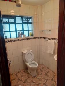 a bathroom with a toilet and a sink and a window at Beautiful spacious room in Nairobi