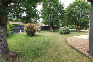a yard with grass and trees and a fence at Belle maison - 5 chambres 4 sdb - proche circuit et pôle européen du cheval - idéal groupes & familles in Champagné