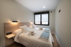 1 dormitorio con 1 cama blanca grande y ventana en Apartamentos Arrigane, en Guernica y Luno