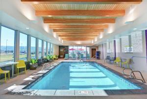 大章克申Home2 Suites By Hilton Grand Junction Northwest的酒店大堂的游泳池，配有桌椅