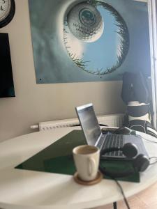 a desk with a laptop and a cup of coffee on it at SGIGOLF Apartments No3 No2 in Wejherowo