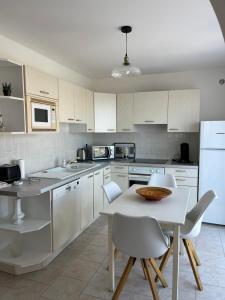 - une cuisine avec des placards blancs, une table et des chaises dans l'établissement Appartement rez de villa, à LʼÎle-Rousse