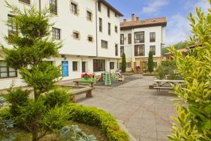 a courtyard of a building with benches and trees at Apartamentos Capriccio in Santillana del Mar