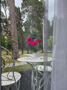 un tavolo con un vaso con fiori rosa di Park Apartments a Kulautuva