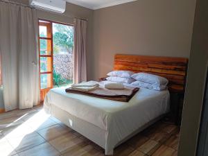 1 dormitorio con 1 cama con sábanas blancas y ventana en 21 On Coetzee Guest House, en Bloemfontein