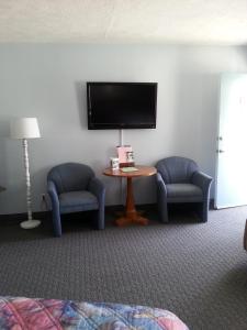 a room with two chairs and a tv and a table at Carolina Motel in Franklin