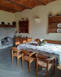 comedor con mesa, sillas y chimenea en Olive Tree Suites Farmstay Villa, en Lamporecchio