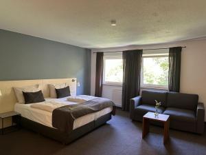 una camera con letto, divano e sedia di Alpenglühen Smart Hotel a Olching