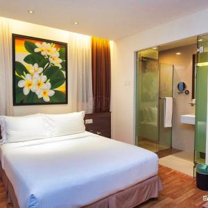 a bedroom with a large white bed and a bathroom at Frenz Hotel Kuala Lumpur in Kuala Lumpur