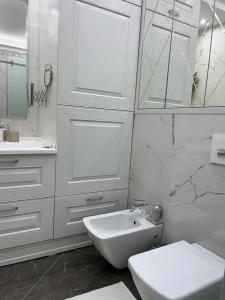 a white bathroom with a toilet and a sink at Apartament in the center of Chisinau in Chişinău