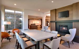 une salle à manger avec une table, des chaises et une cheminée dans l'établissement Hilton Garden Inn Idaho Falls, à Idaho Falls