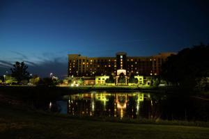 a building at night with a reflection in the water at Embassy Suites by Hilton Minneapolis North in Brooklyn Center