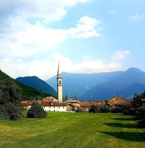 eine Kirche mit einem Kirchturm auf einem grünen Feld mit Bergen in der Unterkunft La Rocconella in Arten