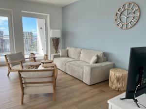 a living room with a couch and a clock on the wall at COAST HOUSE Seaside Loft in Bremerhaven