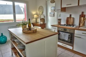 een keuken met een tafel met een fles wijn erop bij Maison cosy proche de la mer in Binic