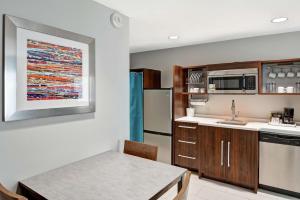 a kitchen with a sink and a refrigerator and a table at Home2 Suites By Hilton Conway in Conway