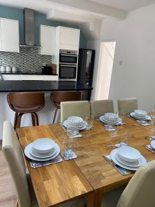 a wooden table with plates and wine glasses on it at Richards Retreat Blackpool in Blackpool