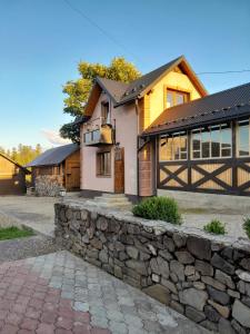 a house with a stone wall and a fence at Кукул in Vorokhta