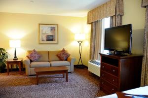 Habitación de hotel con sofá y TV de pantalla plana. en Hampton Inn & Suites Red Bluff, en Red Bluff