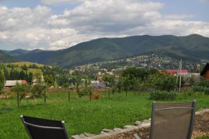 two chairs in a field with mountains in the background at Кукул in Vorokhta