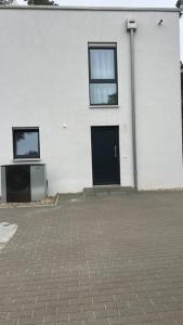 un edificio bianco con una porta nera e una televisione di Modernes Apartment a Rangsdorf