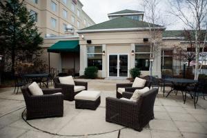 un patio con sillas y mesas de mimbre frente a un edificio en Hilton Garden Inn Rockaway, en Rockaway