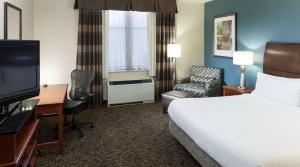 a hotel room with a bed and a desk and a tv at Hilton Garden Inn Rockaway in Rockaway