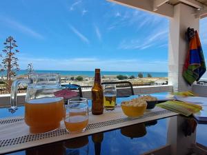 una mesa con bebidas en un balcón con vistas a la playa en Holiday Portfolio Da Gama Bay, en St Helena Bay