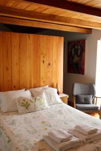 a bedroom with a bed with a wooden headboard and a chair at Casa da Eira in Marco de Canaveses