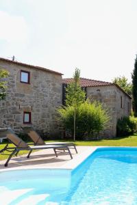 una piscina frente a una casa de piedra con 2 tumbonas en Casa da Eira, en Marco de Canaveses