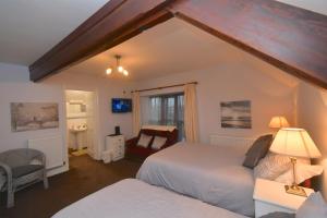 1 Schlafzimmer mit 2 Betten, einem Stuhl und einem Fenster in der Unterkunft The Old Board School Guest House in St Clears