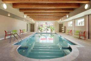 a swimming pool in a house with chairs and a table at Home2 Suites By Hilton Menomonee Falls Milwaukee in Menomonee Falls