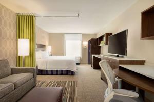 Menomonee FallsHome2 Suites By Hilton Menomonee Falls Milwaukee的配有床和电视的酒店房间