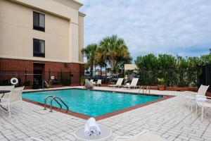 a swimming pool with white chairs and a building at Hampton Inn & Suites Port Arthur in Port Arthur