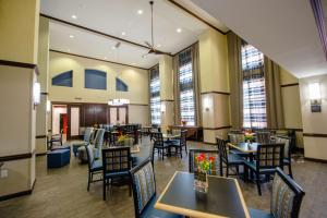 um restaurante com mesas, cadeiras e janelas em Hampton Inn & Suites Port Arthur em Port Arthur