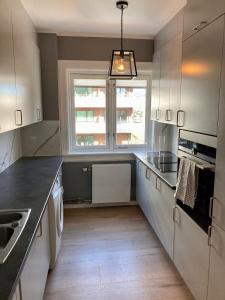 een keuken met witte kasten en een raam bij Majorstua, charming and modern 2 bedroom apartment in Oslo