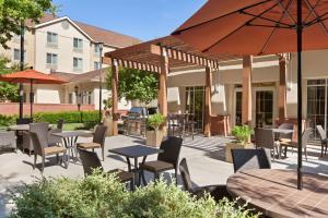 een patio met tafels en stoelen en een parasol bij Homewood Suites Medford in Medford