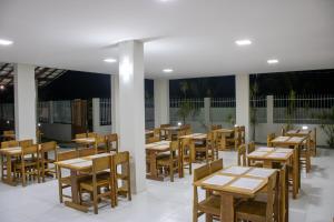 a restaurant with wooden tables and wooden chairs at Paraiso Barra Hotel in Barra de Santo Antônio