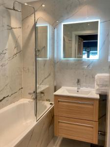 een badkamer met een bad, een wastafel en een douche bij Majorstua, charming and modern 2 bedroom apartment in Oslo