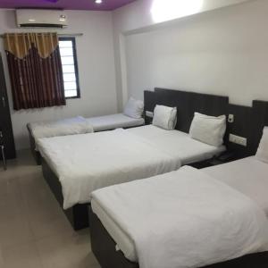 a room with three beds and a couch at Hotel Long Stay in Ahmedabad