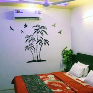 a bedroom with palm trees stenciled on the wall at Hotel Long Stay in Ahmedabad