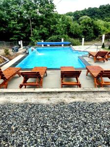 a swimming pool with wooden tables and chairs in it at Casa de oaspeti Abby cu piscina si jacuzzi in Moldoveneşti