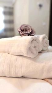 una pila de toallas en una cama con una rosa en Casa de oaspeti Abby cu piscina si jacuzzi, en Moldoveneşti