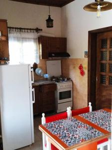 a kitchen with a white refrigerator and a table with a table sidx sidx at Gold Coast cottage house, ideal for families in Sozopoli
