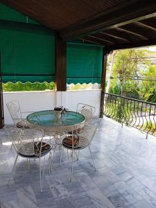 a patio with a glass table and chairs on a porch at Gold Coast cottage house, ideal for families in Sozopoli