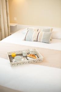 ノワールムーティエにあるHotel Autre Merのベッドの上に朝食用の食材を入れたトレイ