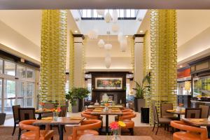 un restaurante con mesas, sillas y columnas amarillas en Hilton Garden Inn Indianapolis/Carmel, en Carmel