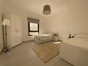una camera da letto bianca con due letti e una finestra di Qaimariya Farmhouse Amman - Day Use - Lodging - Events ad Amman