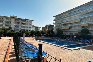 a swimming pool with blue chairs and a building at Apartamento acogedor , Blanes in Blanes