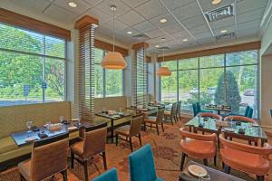 restauracja ze stołami i krzesłami oraz dużymi oknami w obiekcie Hilton Garden Inn by Hilton Mount Laurel w mieście Mount Laurel
